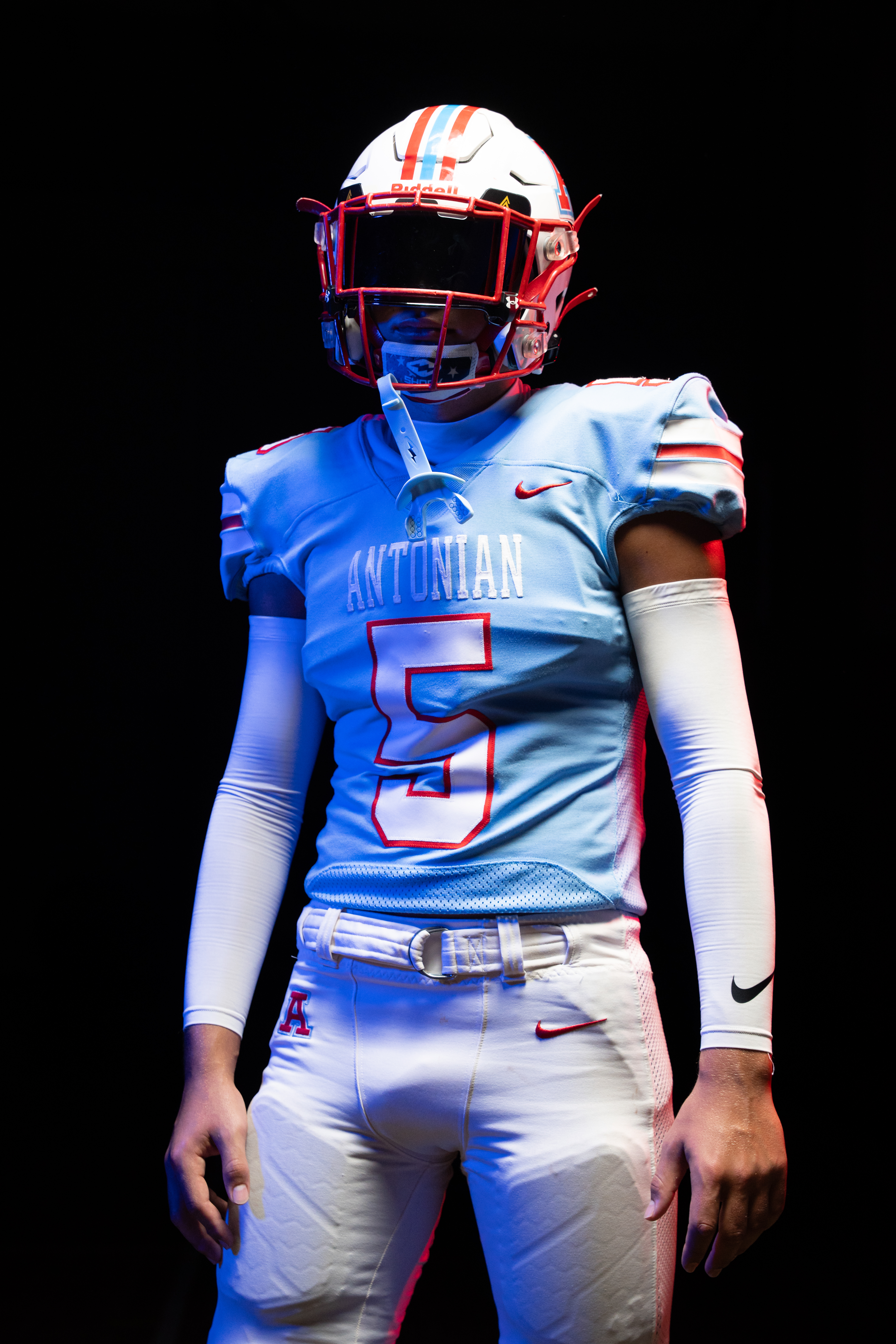 Antonian football athlete wearing number five under red and blue media day lighting